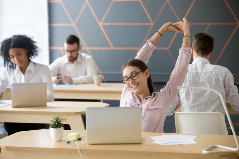 millennial employee stretching taking break from computer work relaxation scaled